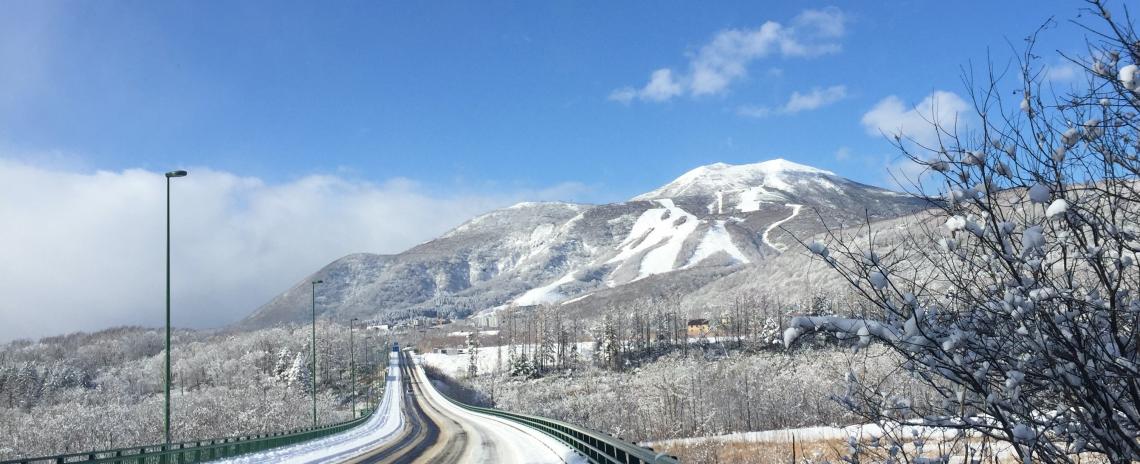 A snowy road leading to Hirafu ski resort with mountain to the right