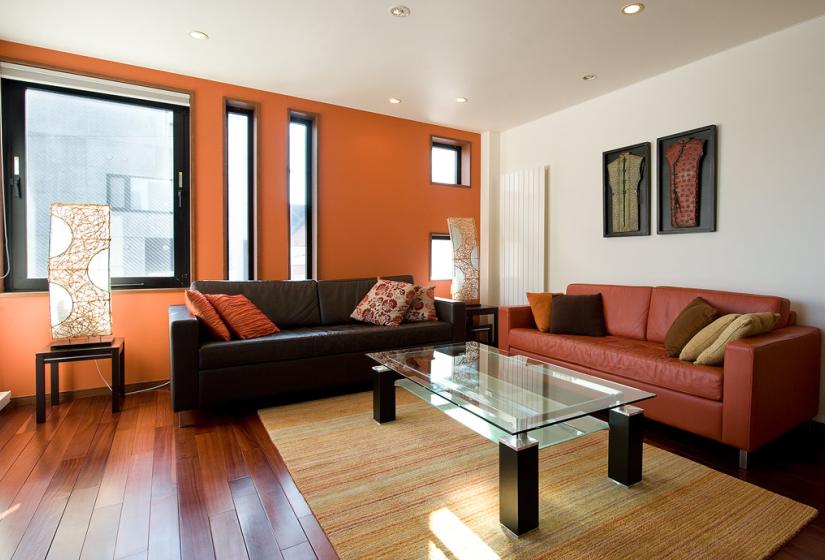 Living area with glass coffee table red and black leather sofa and wall art