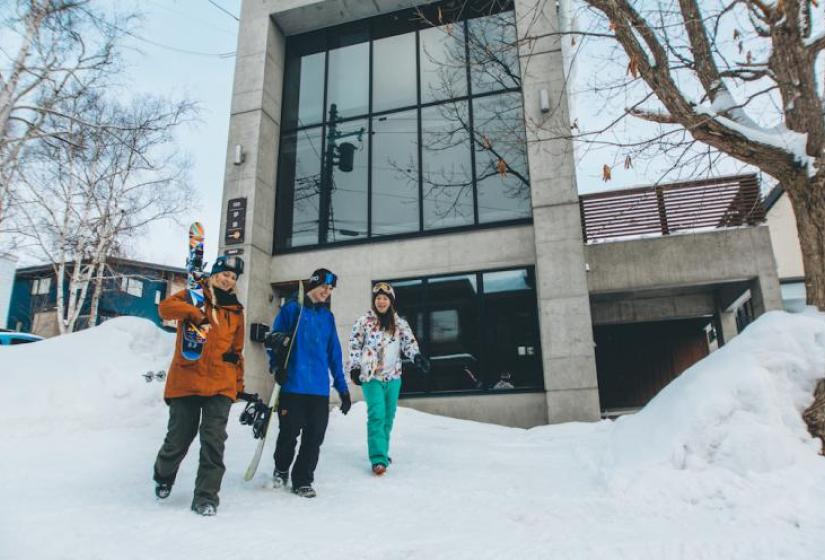 3 people walking with large concrete home behind