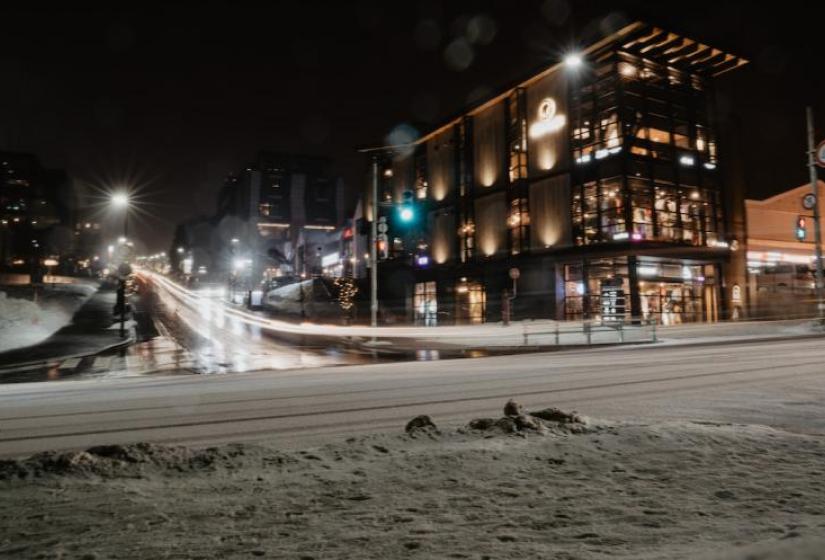 A snowy road with 3 story lit up building to the right