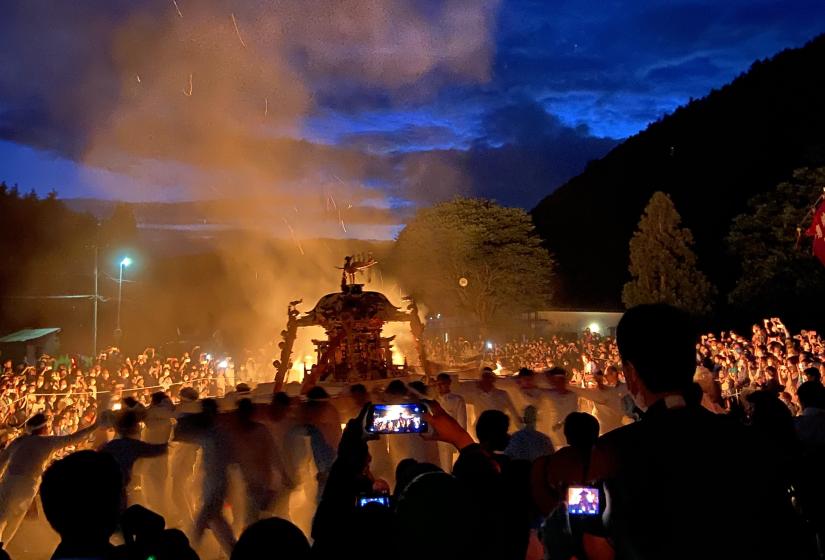 A portable shrine is back lit by fire at night