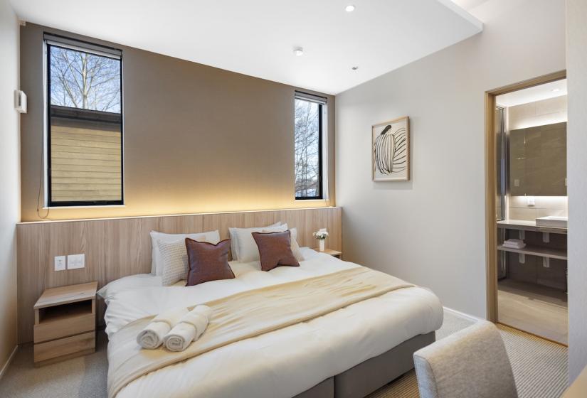 A made up double bed with beige throw